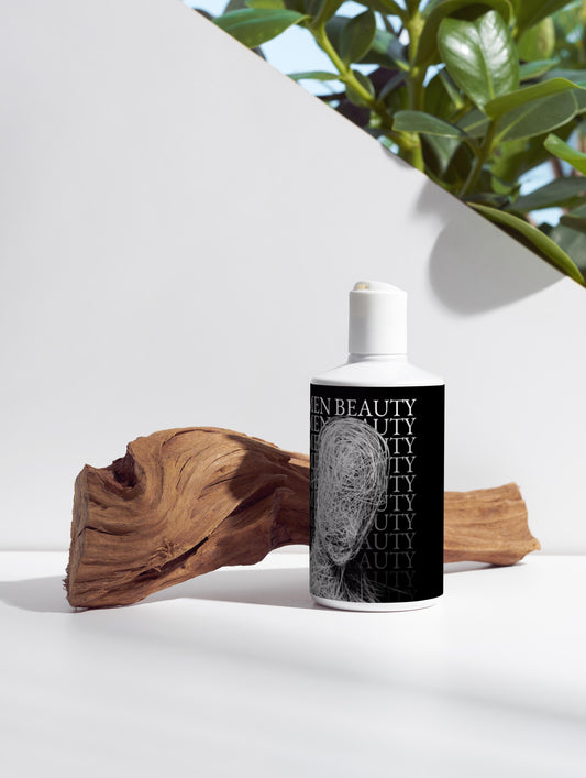 Skincare bottle with black label on a white surface with a plant in the background, Volumize Shampoo.