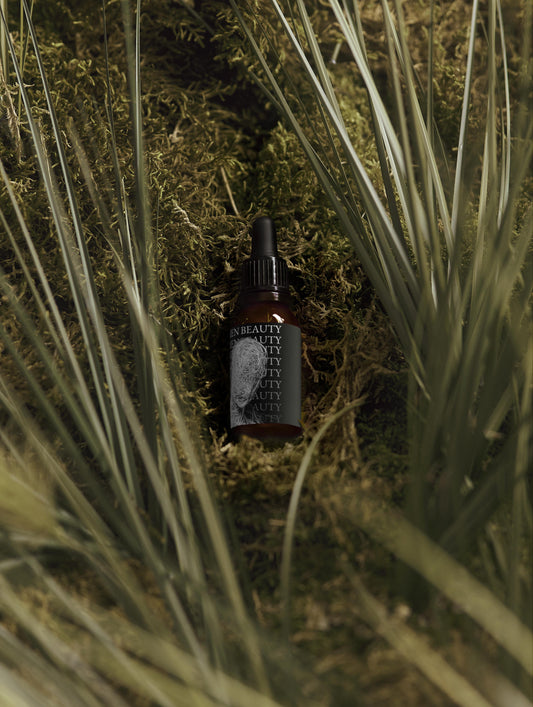 Brown bottle with dropper on a grassy background, Softening Beard Oil.