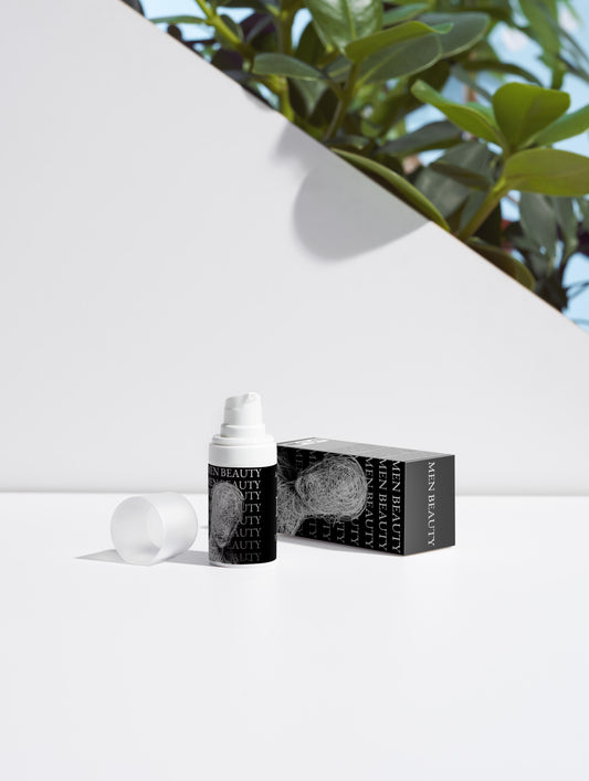 Skincare bottle and packaging on a white background with greenery in the corner, Acne Spot Care.