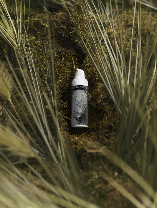 Skincare bottle with a face on it lying on grass, Vitamin C Serum.