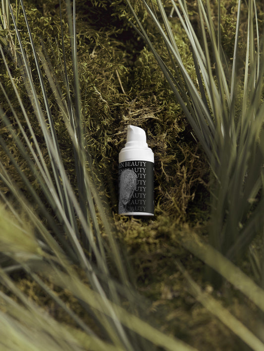 Skincare bottle with 'Men Beauty' branding on a natural background of grass and moss, Acne Spot Care.